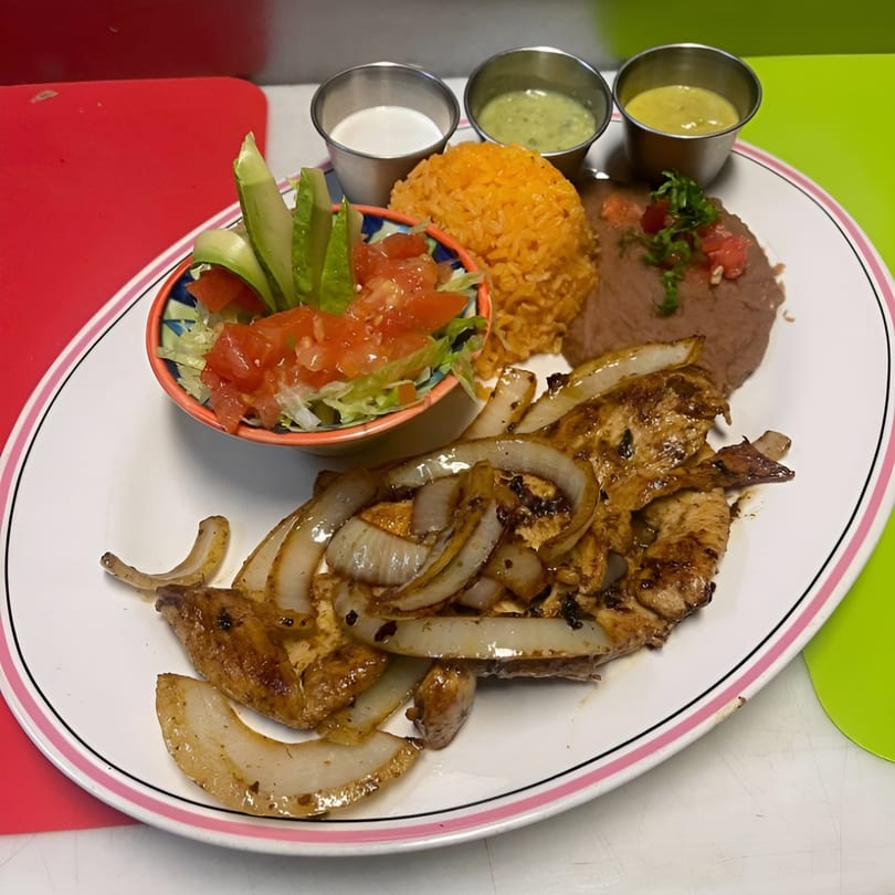 Mexican dish with grilled chicken and onions, rice, refried beans, salad, and three dipping sauces.