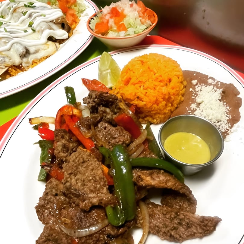 El Don Quijote's sizzling beef fajitas with rice, beans, lime, and a side of cheese dip.